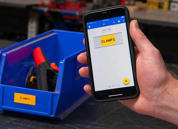 A label design on an Express Labels Mobile screen next to the actual printed label. Both are a vivid yellow and say “CLAMPS”.